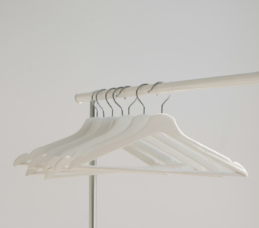 White hangers on a clothing rack — empty space and apparel form